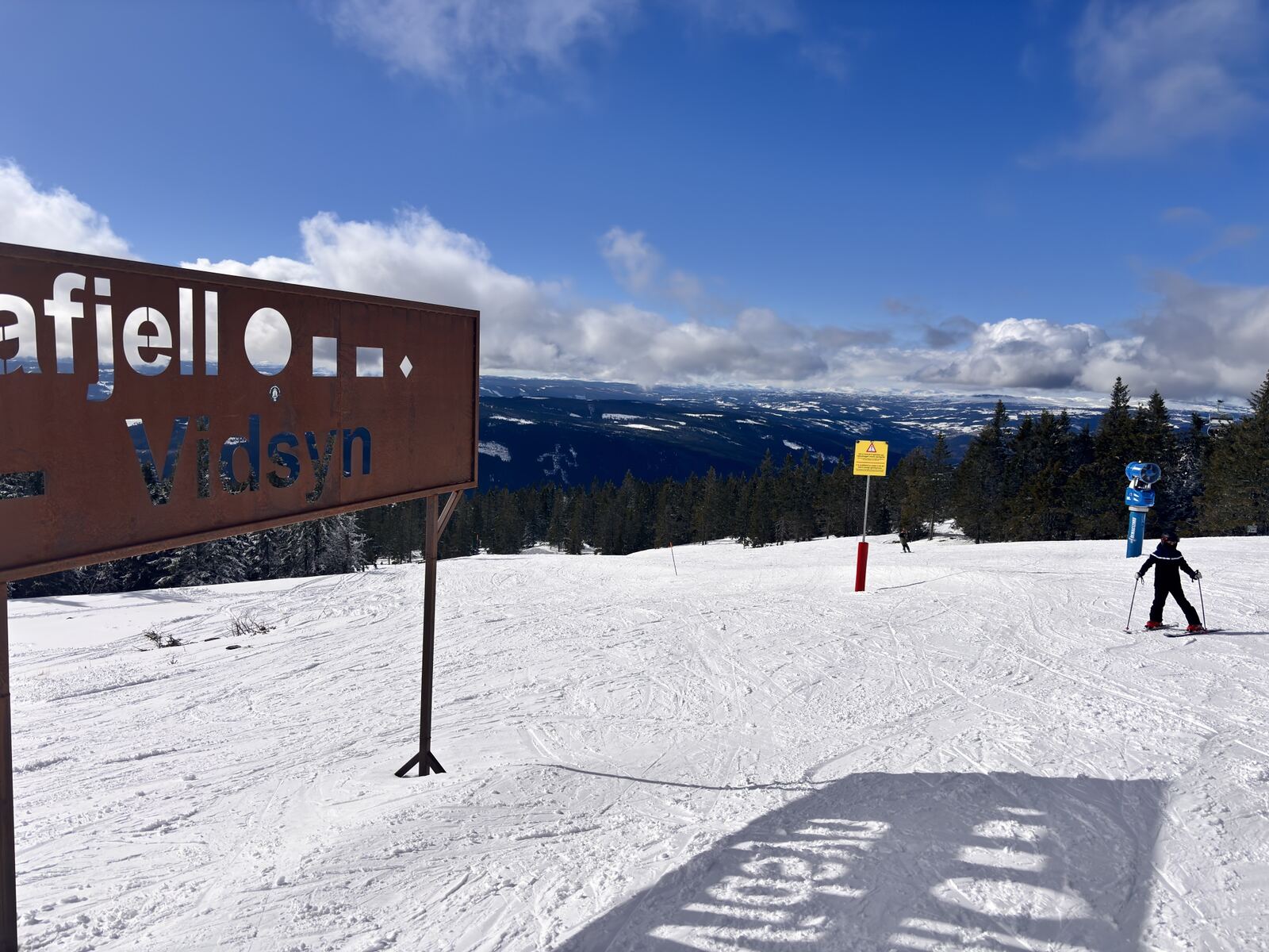 Skiløper ved Vidsyn-skiltet med utsikt over dalen