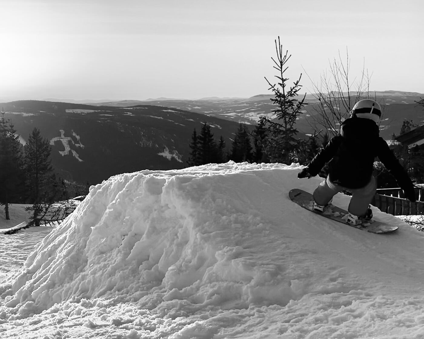Barn på snowboard på en hopp med utsikt over dalen