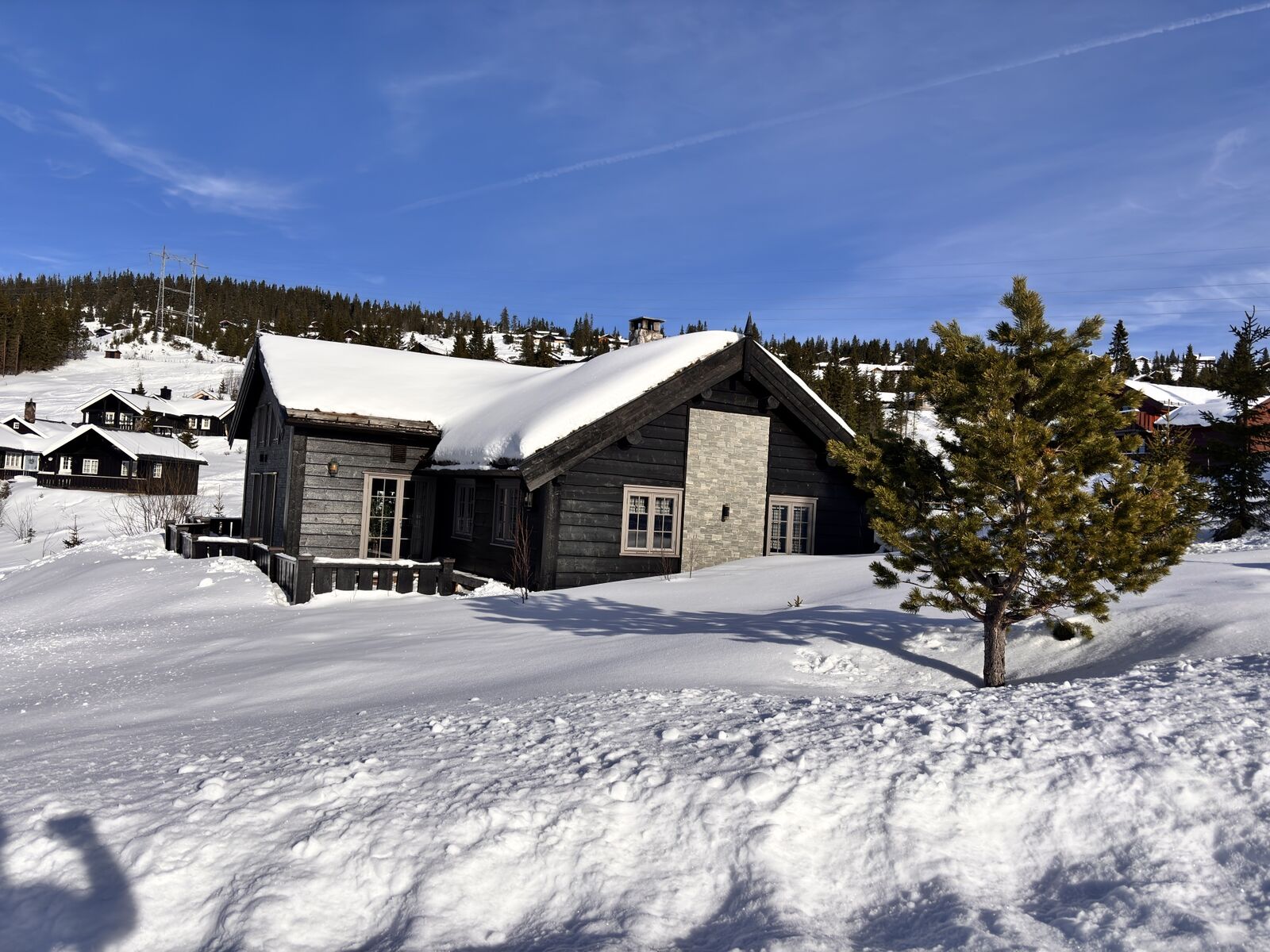 Hytta i dyp snø en klar vinterdag